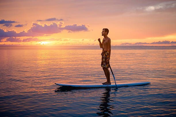Young man stand up on paddle board and paddling out in tropical waters. Water sport in sevan and parz lake