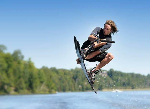 A young man in mid-air during a wakeboarding jump.