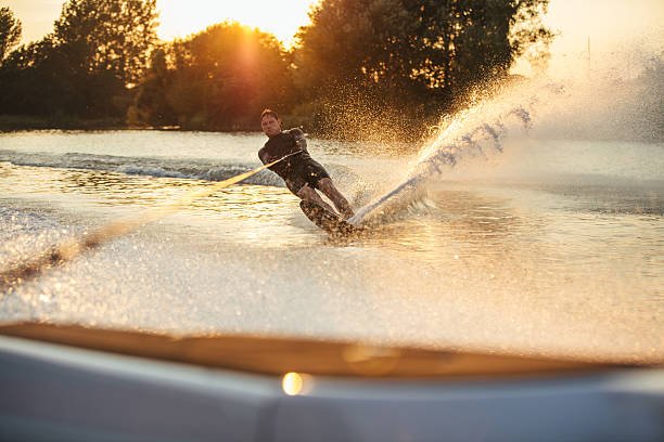 Man wakeboarding on lake behind boat. Water skiing on sevan lake at sunset.
