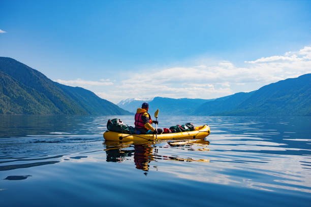 Alone man on kayak boating in Sevan Lake. Calm spring weather, reflection of canoe on a bit ripple water.